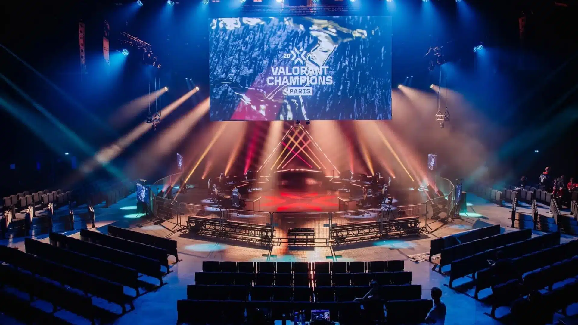 Global Esports Faces Elimination After Champions Shanghai Opener An esports stage for VALORANT Champions Paris with a large screen, red and blue lighting, and empty seating.